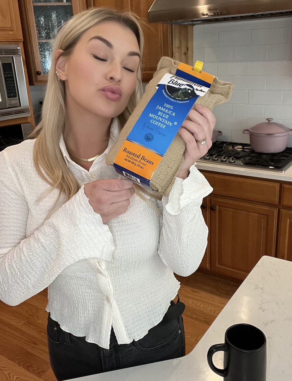 Happy customer holding a bag of Plantation Blue 100% Jamaica Blue Mountain Coffee